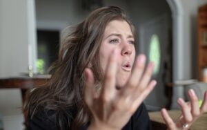 Eine braunhaarige Frau gestikuliert wütend