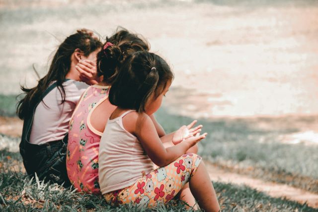 Kinder sitzen auf der Wiese und spielen